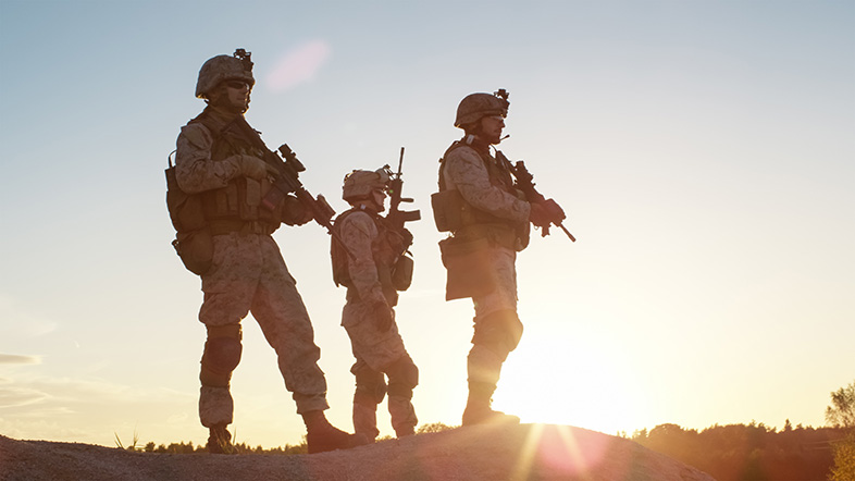 Three armed soldiers standing in the desert abroad