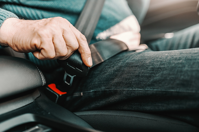 Older man driving safely by buckling up before he drives