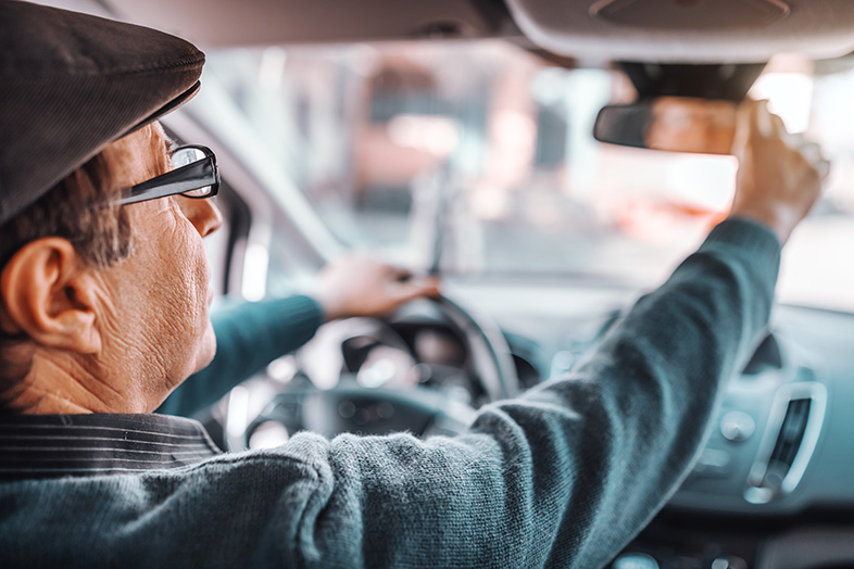 Senior man adjusting his rearview mirror to be a safe driver