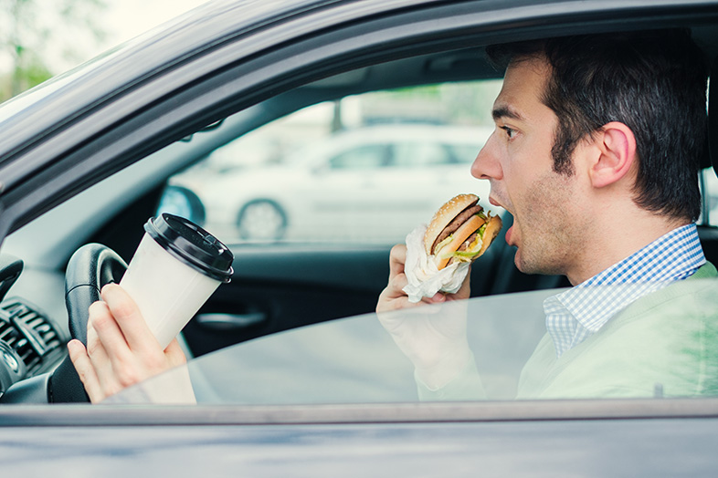 Wisconsin man eating a burger and drinking a coffee while driving
