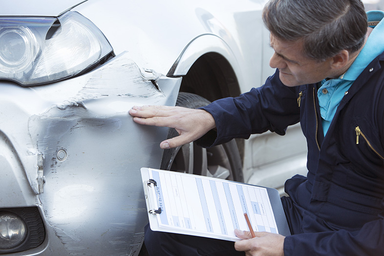 Insurance adjuster noting a car's damages after a hit-and-run accident