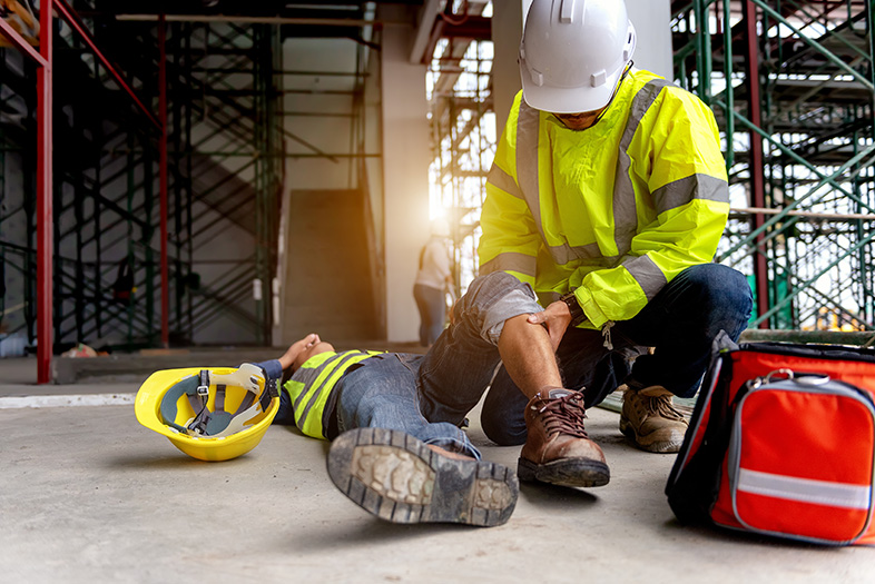 Injured construction worker being helped by a coworker after an accident