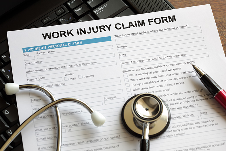 Work injury claim form on a computer keyboard with stethoscope and pen on top of it