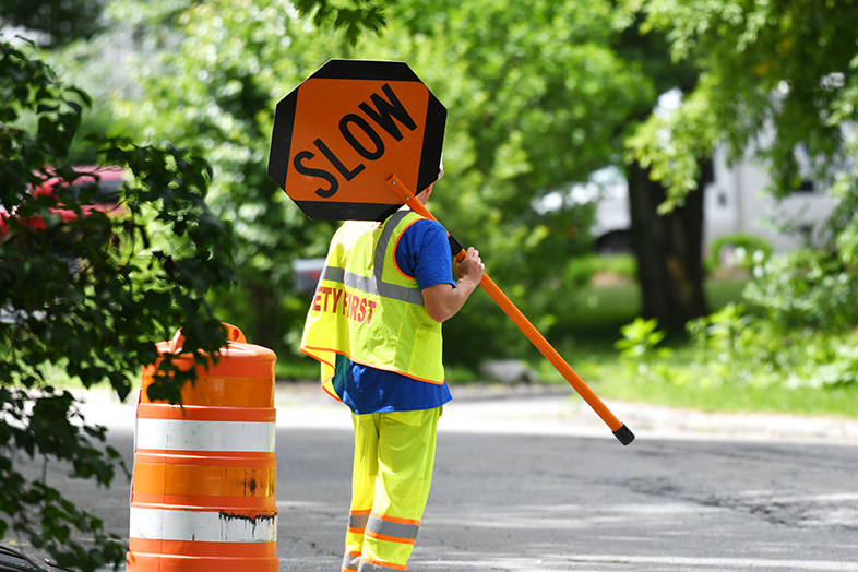 Construction worker holding a "slow" traffic sign to warn oncoming traffic of road work