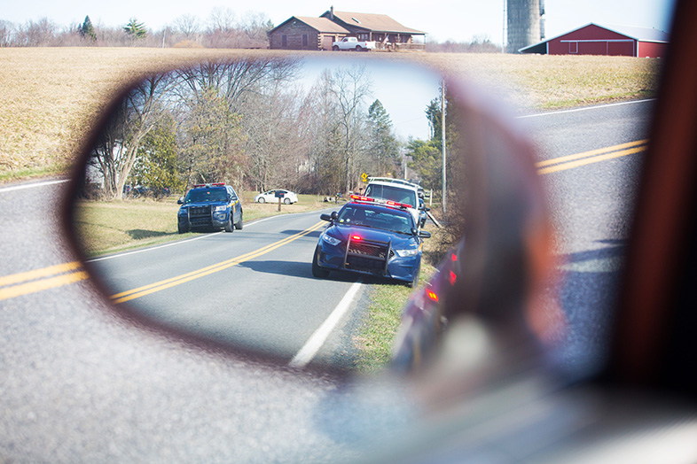 View from a car's side mirror of two police cars with flashing lights during a traffic stop