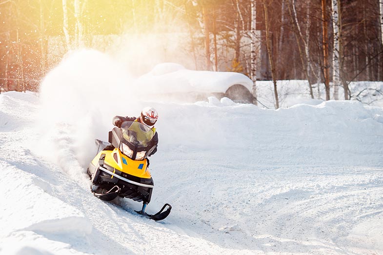 Snowmobile whipping around the corner of a groomed Minnesota trail.