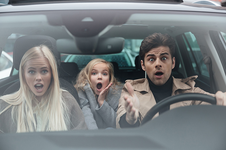 Shocked scared young man sitting in car with family