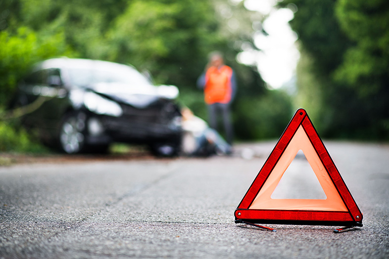 Red emergency triangle on a rural road in front of a car after an accident