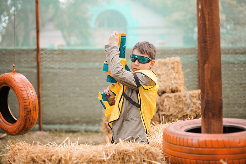 Young boy with toy dart gun wearing protective glasses