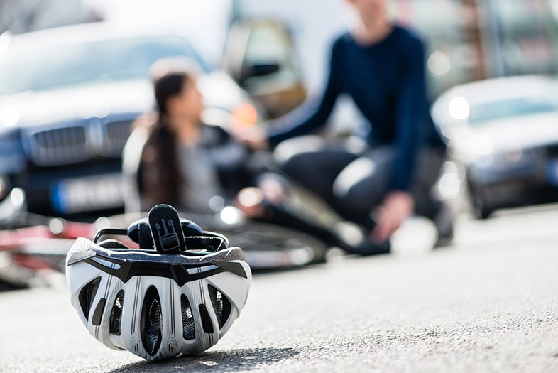 Helmet in the street after a bicycle accident in front of the driver and victim talking