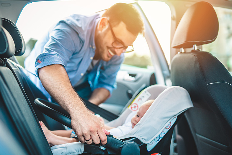 Wisconsin father securing his baby in a rear-facing car seat