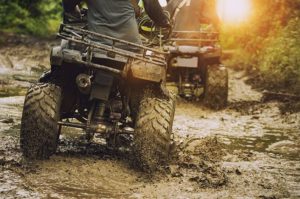 Two ATVs riding through the mud on a Wisconsin ATV trail