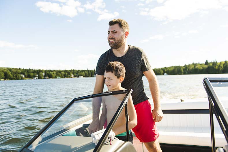 Father teaching his son how to drive a boat on a Wisconsin lake