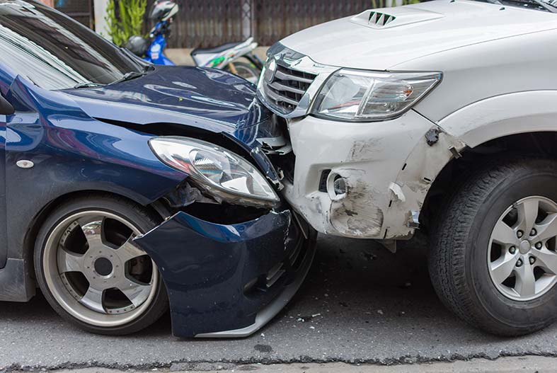 A head-on collision between a blue car and a white car