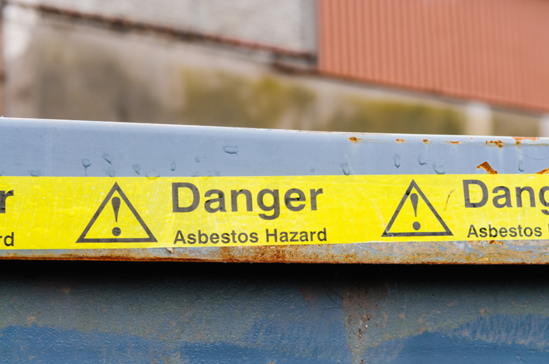 Warning tape across a bin at an asbestos clean-up for a medical facility