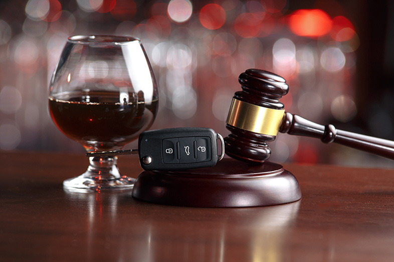 Gavel and set of keys sitting next to an alcoholic beverage
