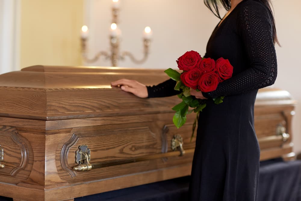 woman with hand on casket mourning