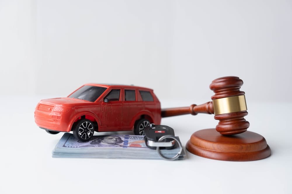 Wooden hammers, toy cars, money, contracts, auction ideas, and US dollars amid car accident insurance claims lawsuits in court.