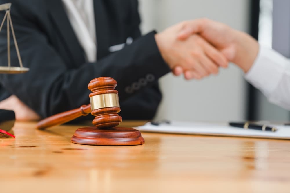 Law and justice concept, businessman shaking hands with a lawyer to finalize an agreement, symbolizing a legal partnership or contract discussion.