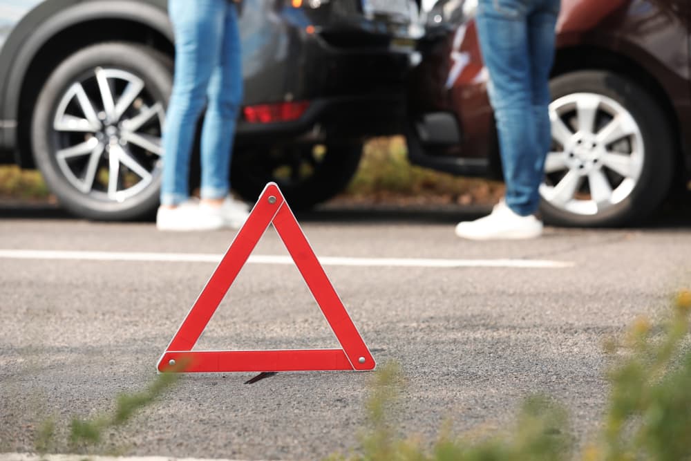 Emergency stop sign near two persons arguing about car accident on road