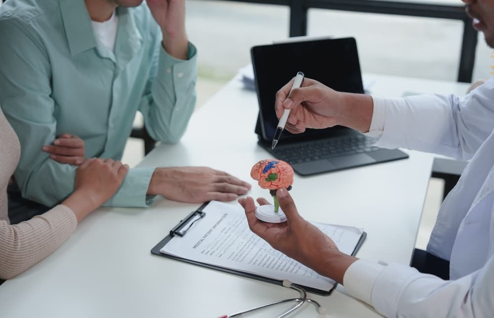 Doctors reviewing a brain X-ray of a patient with a concussion from an accident, discussing symptoms and treatment options for healthcare.