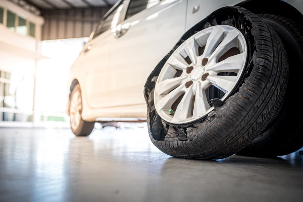 Close-up of flat tires on an old car, highlighting the damage caused by an accident and the condition of the tires.