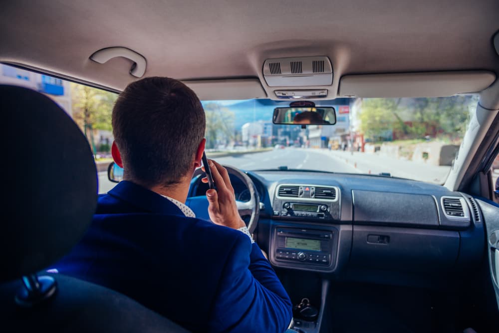 Reckless businessman driving in the city during the rush hour while talking on his phone.