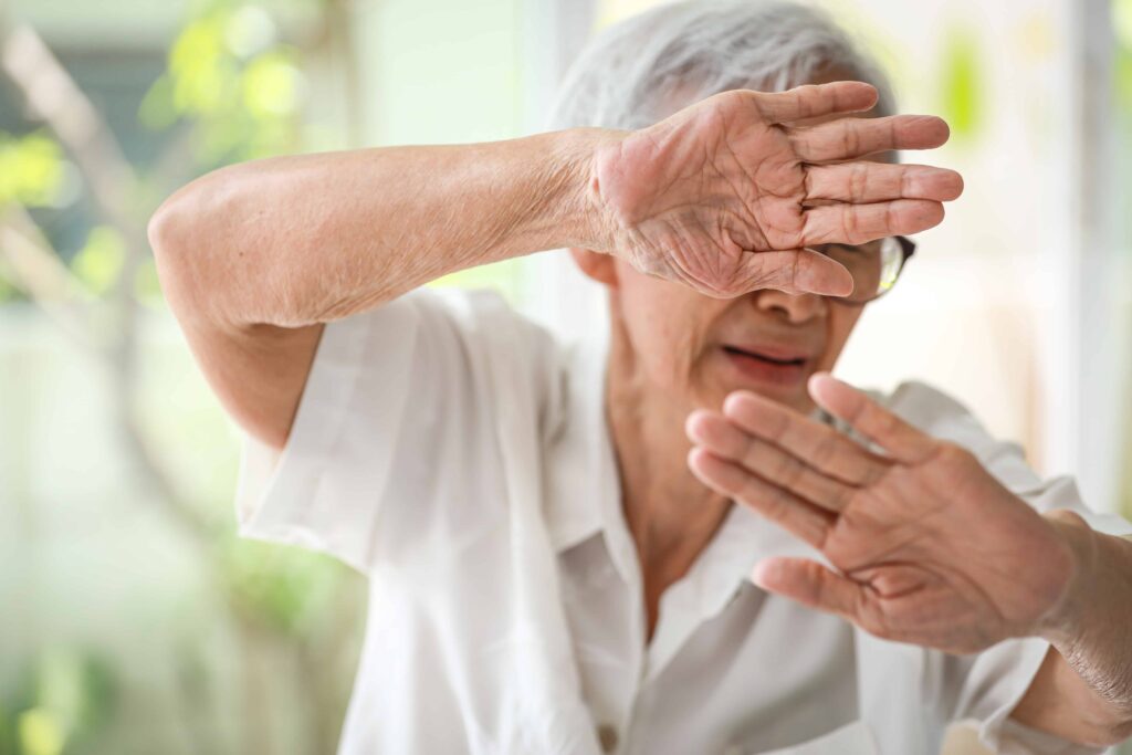Elderly woman shielding herself in fear, representing nursing home abuse or elder neglect.