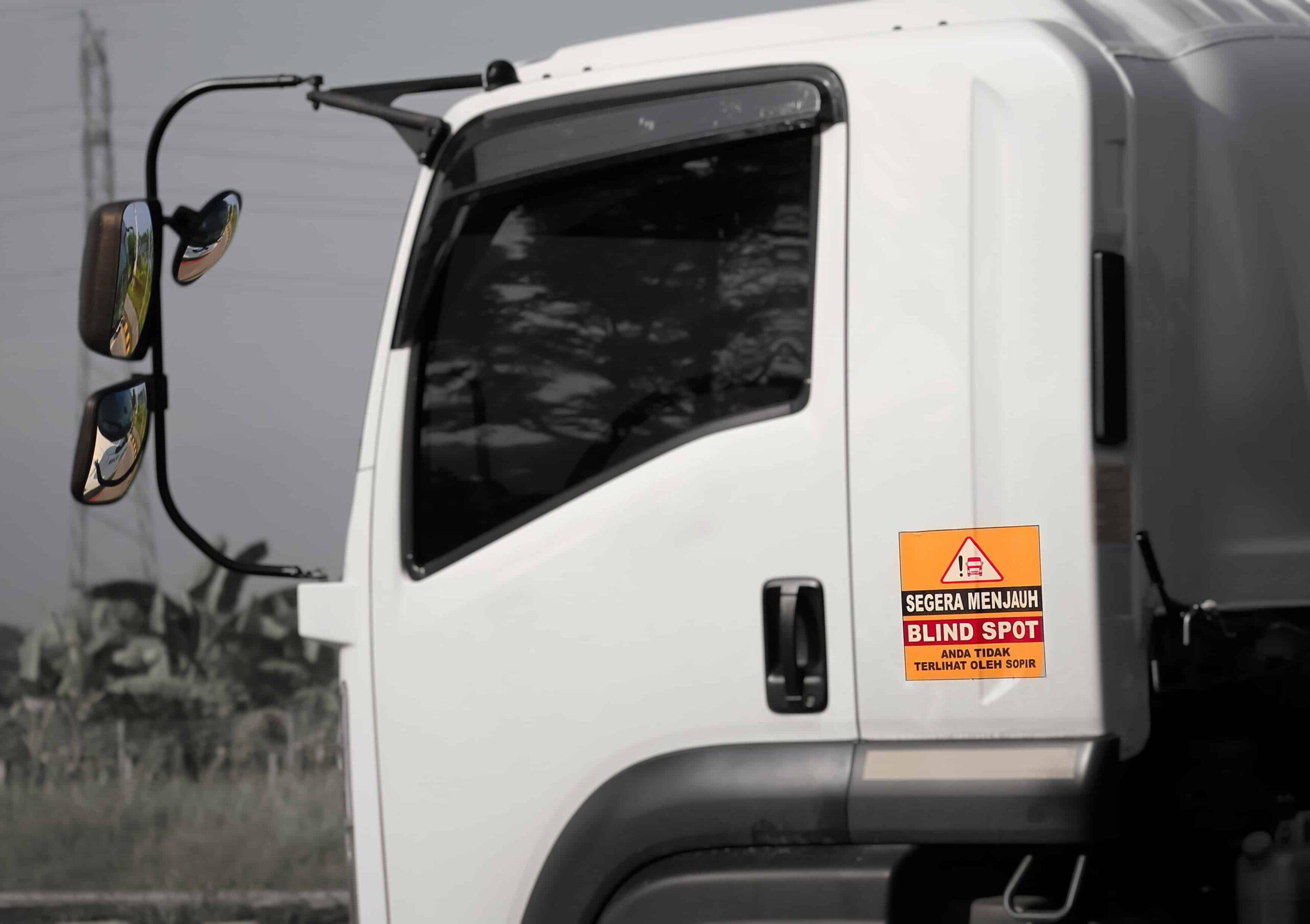 Commercial truck with blind spot warning sticker on the cab door, highlighting large truck blind spot safety risks.