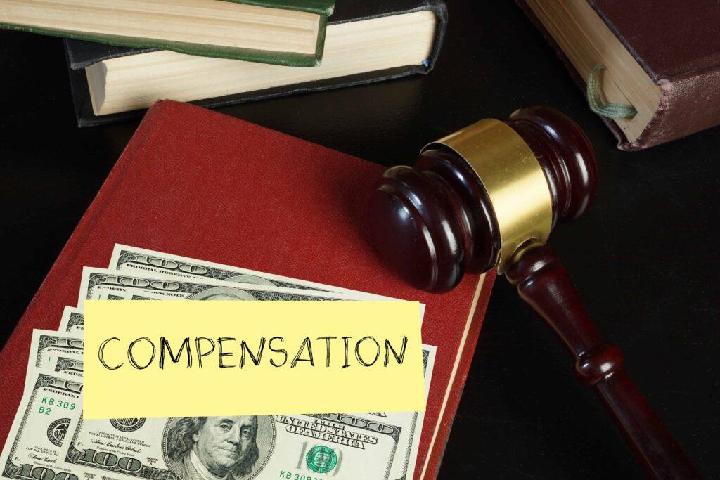 Legal compensation concept with a judge’s gavel, law books, and cash labeled ‘compensation,’ representing a personal injury or legal settlement. Legal compensation concept with a judge’s gavel, law books, and cash labeled ‘compensation,’ representing a personal injury or legal settlement.