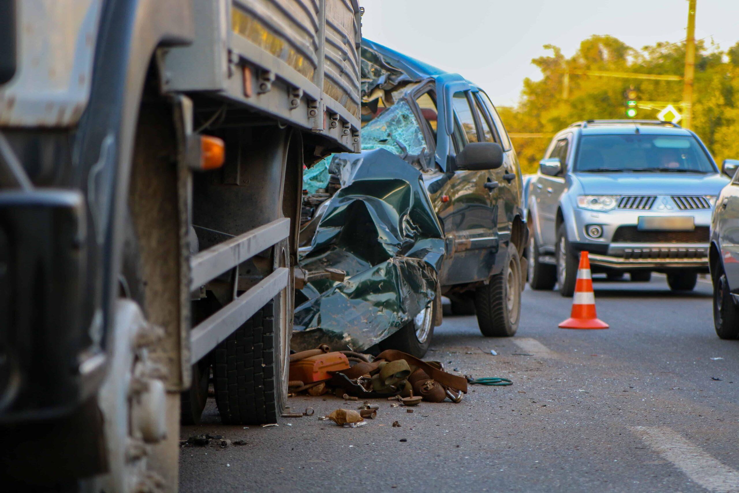 Severe car accident involving a pickup truck rear-ended by a commercial truck, showing major vehicle damage at the crash scene