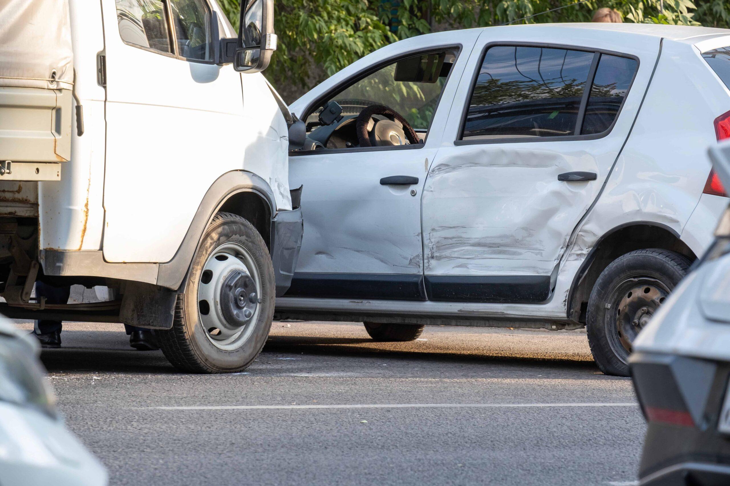 Side-impact car accident between a white SUV and a delivery truck, showing vehicle damage from a traffic collision.
