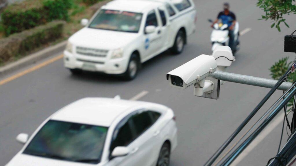 Traffic surveillance camera monitoring vehicles on a city road for speed enforcement, accident prevention, and public safety