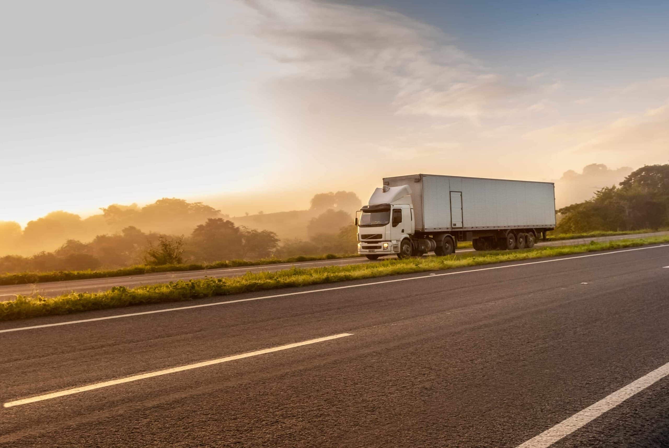 Semi-truck driving on highway at sunrise, representing commercial trucking, road transportation, and truck accident risk on rural roads