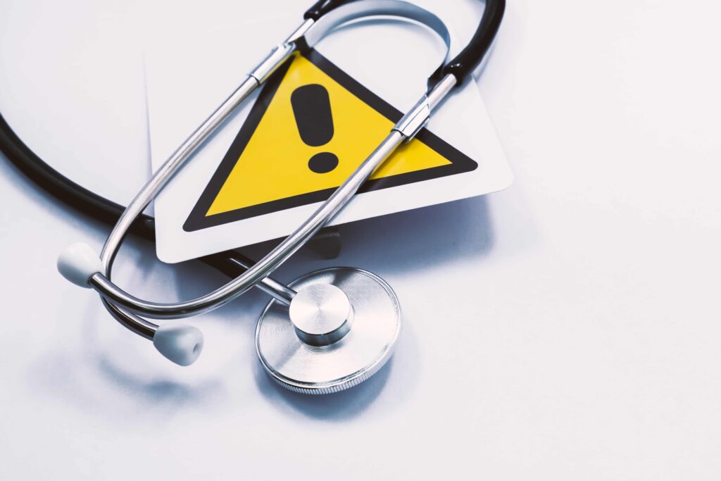 Stethoscope on medical warning sign symbolizing healthcare risks, patient safety concerns, and medical negligence concept Stethoscope on medical warning sign symbolizing healthcare risks, patient safety concerns, and medical negligence concept