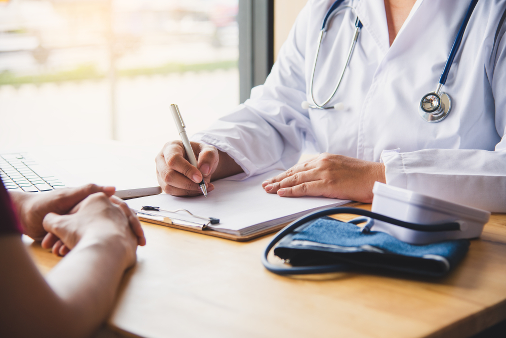Doctor fills out paperwork while discussing patient medical history